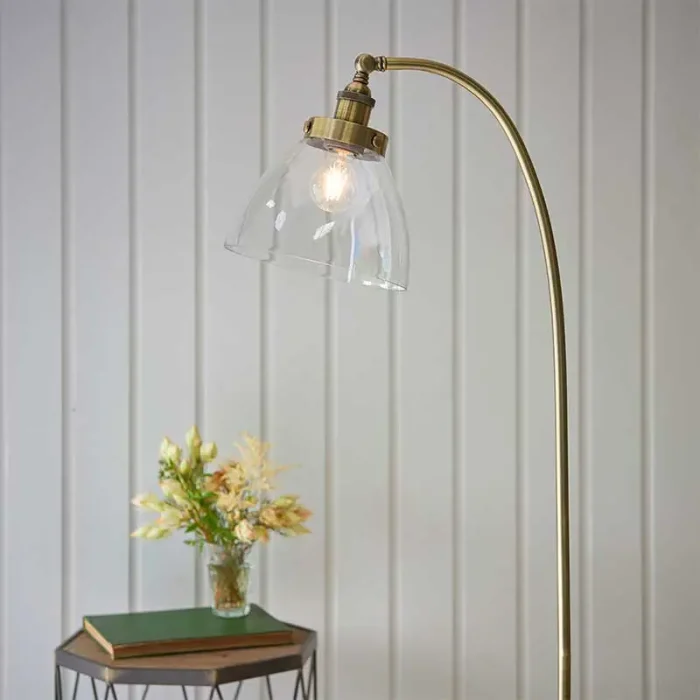 Floor lamp in antique brass finish with clear glass shade and adjustable knuckle joint