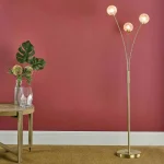 Floor lamp in satin brass finish feature three curved arms, each adorned with frosted glass shade