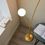 Floor lamp in brushed gold finish with white glass shades