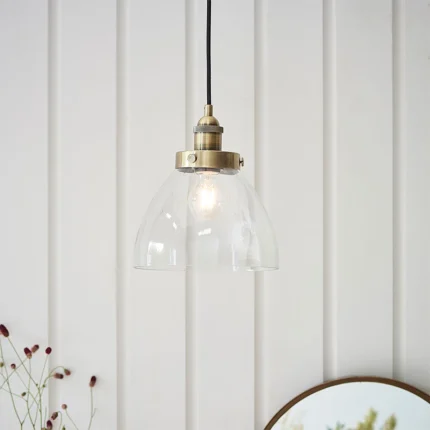 Single pendant light in antique brass finish with clear glass shade