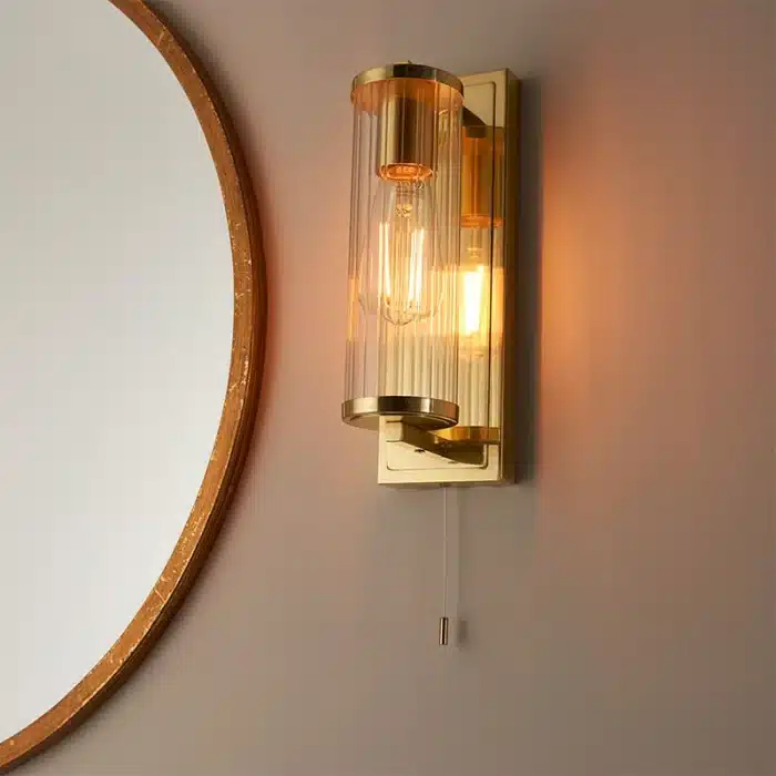 Bathroom wall light in brushed gold finish with clear glass shade