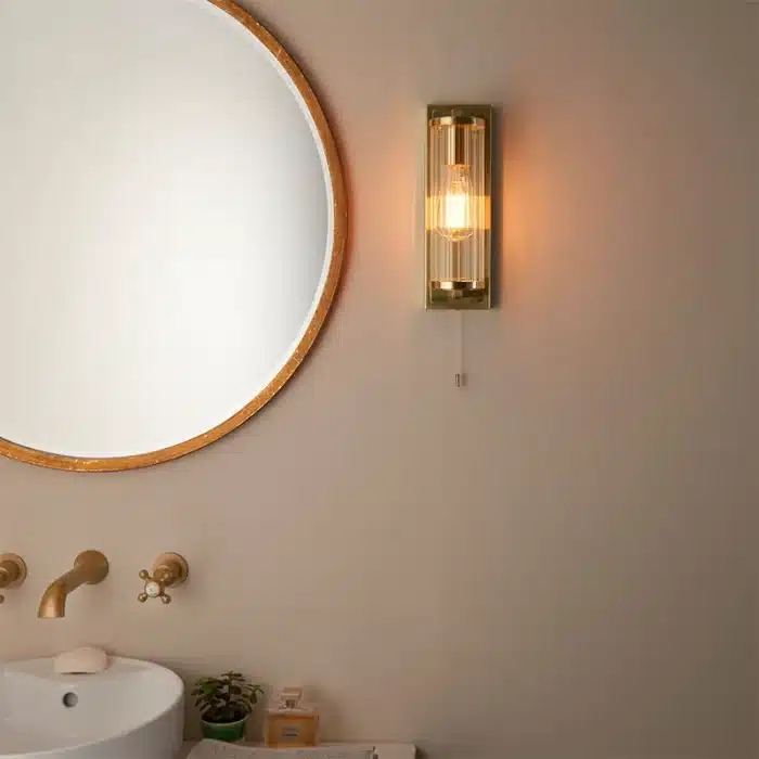 Bathroom wall light in brushed gold finish with clear glass shade