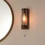 Bathroom wall light in dark bronze finish with clear glass shade