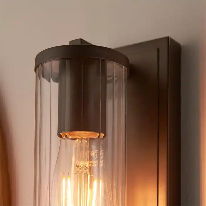 Bathroom wall light in dark bronze finish with clear glass shade