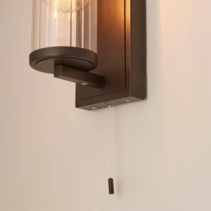 Bathroom wall light in dark bronze finish with clear glass shade