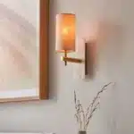 Brass marble effect wall light with linen shade in bedroom close up