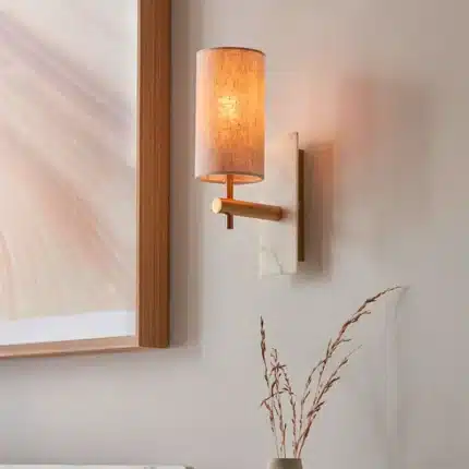 Brass marble effect wall light with linen shade in bedroom close up